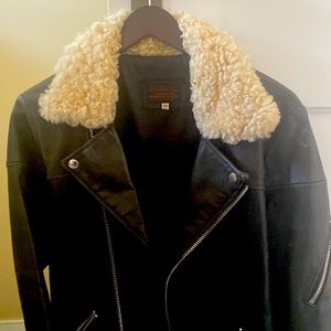 A black leather motor cycle jacket with fake fur collar
